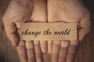Hands holding piece of paper with words Change the World